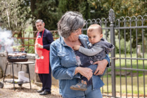 Grandmother carrying baby boy at family BBQ gathering, Florence, Italy Grandmother carrying baby boy at family BBQ gathering, Florence, Italy